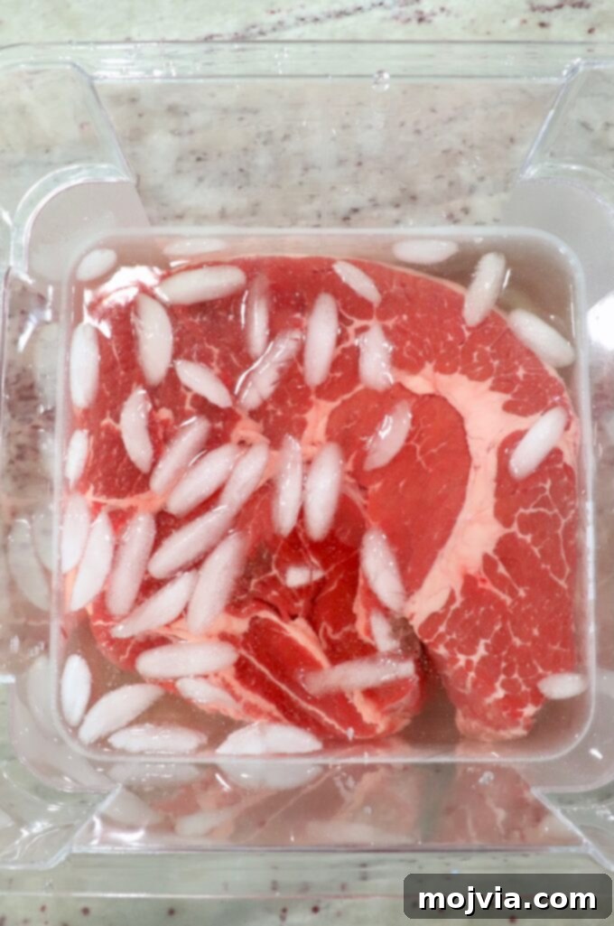 Smoked Beef Chuck Roast Perfection 3 Chuck roast submerged in a brine solution with ice cubes in a large plastic tub.
