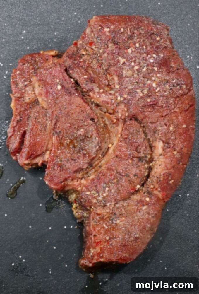 A perfectly smoked chuck roast, removed from the smoker and resting on a cutting board, showcasing its rich, dark bark.