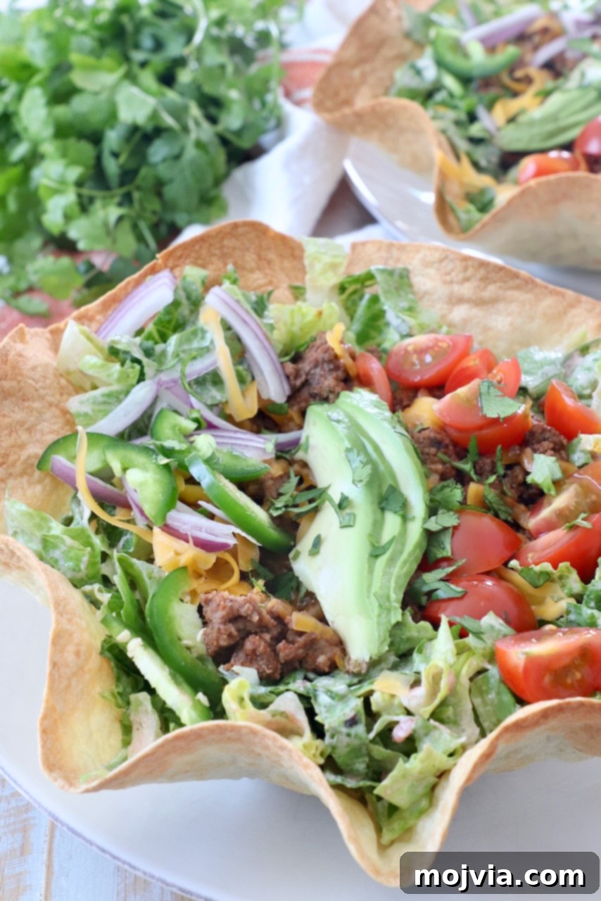 Hearty Beef Taco Salad 10 A perfectly assembled taco salad in a crispy tortilla shell bowl, presented on a white plate, ready to be enjoyed.