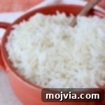 Fluffy Instant Pot Basmati Rice 8 cooked white rice in orange bowl with spoon