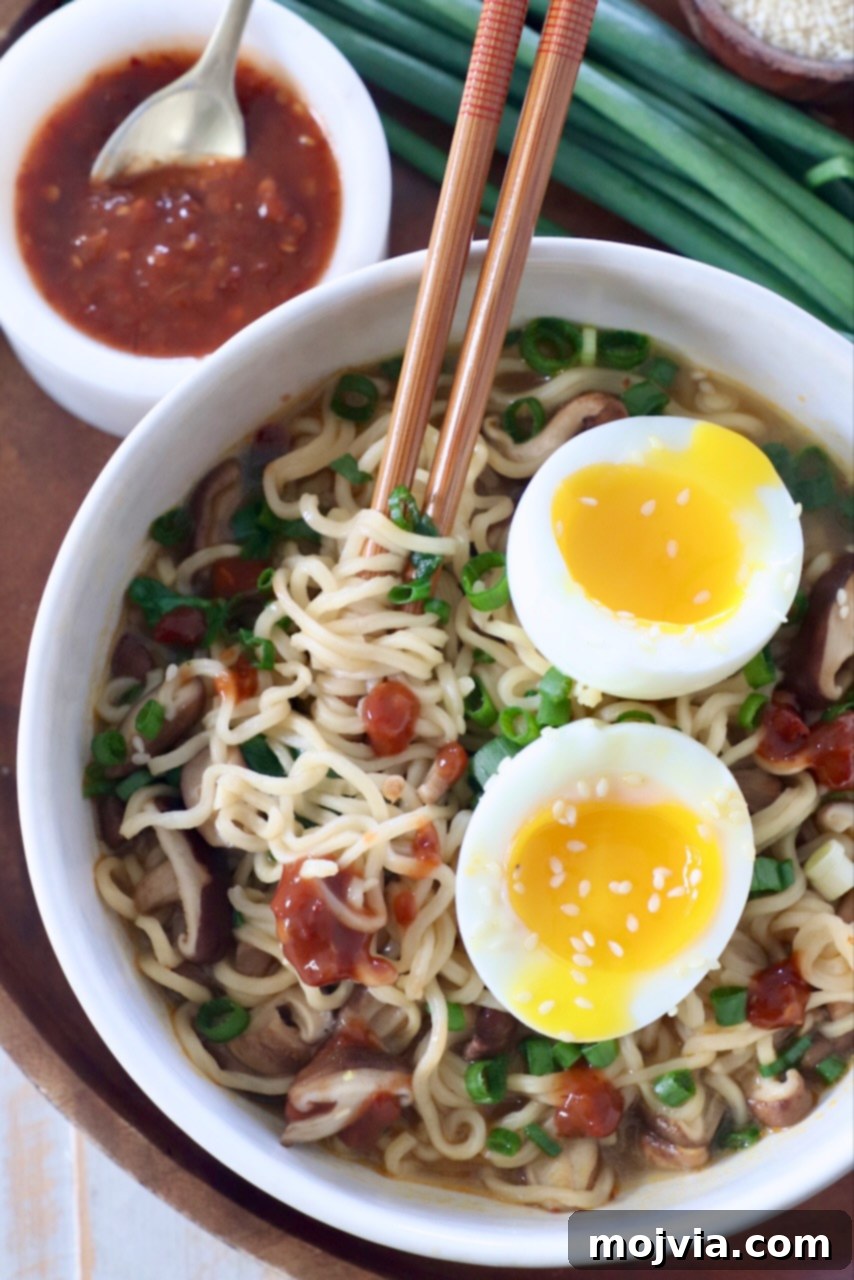 Plant-Based Ramen Perfection 2 A steaming bowl of Vegetarian Ramen with vibrant broth, noodles, mushrooms, spinach, and a perfectly halved soft-boiled egg, garnished with green onions. Chopsticks are poised to pick up noodles.