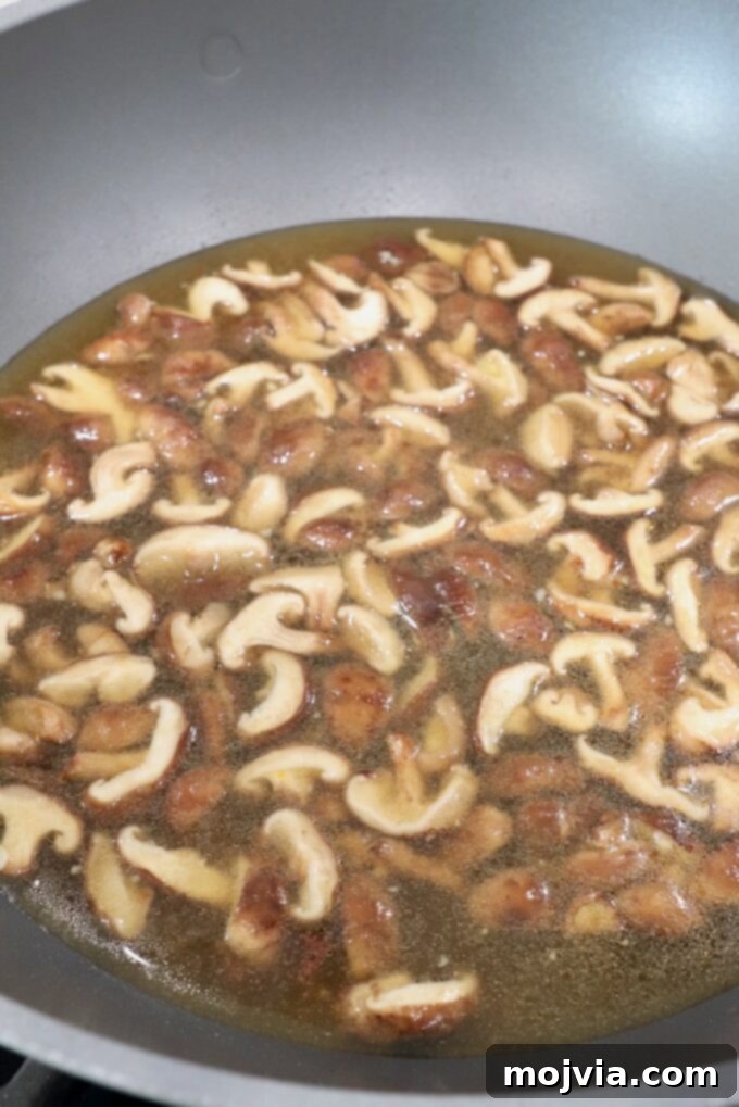 Plant-Based Ramen Perfection 4 Sliced shiitake mushrooms sautéing in a large pot or wok on the stove, beginning to caramelize, ready to absorb the rich broth flavors.