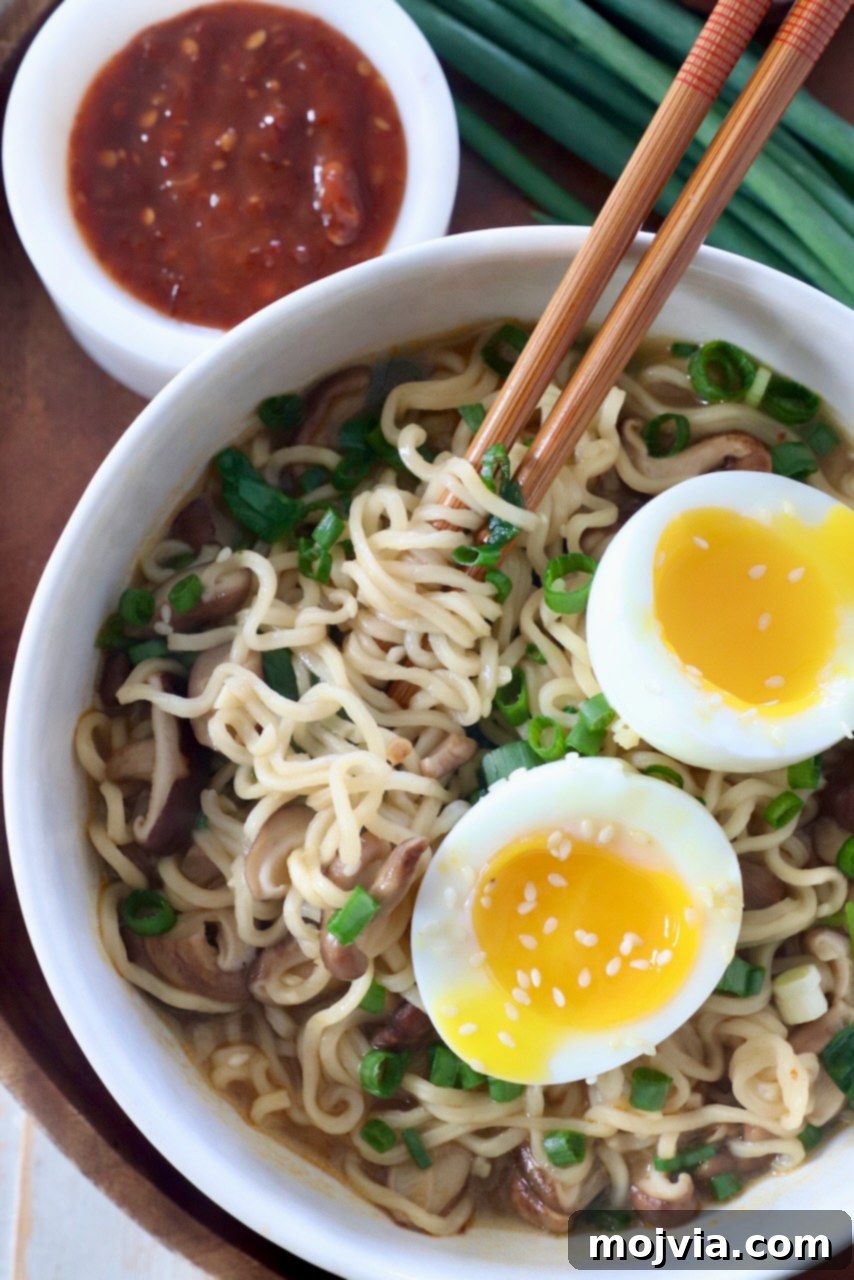 Plant-Based Ramen Perfection 6 A perfectly plated bowl of homemade vegetarian ramen, complete with rich broth, noodles, mushrooms, spinach, and a soft-boiled egg, garnished with fresh green onions and sesame seeds. Chopsticks rest on the bowl's edge.