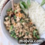 Spicy Thai Basil Chicken Stir-fry 9 Cooked ground chicken with Thai basil and green beans in a bowl with cooked white rice, ready to serve.