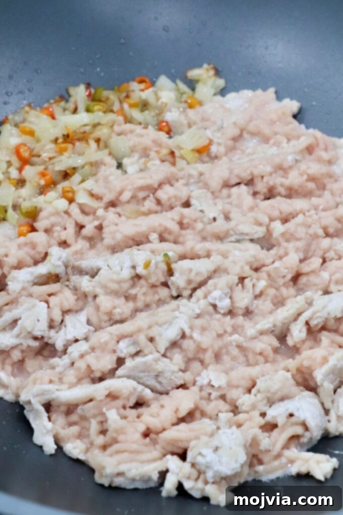 Spicy Thai Basil Chicken Stir-fry 5 Ground chicken and vegetables beginning to cook in a large skillet, illustrating the initial stir-frying step for the Pad Krapow Gai.