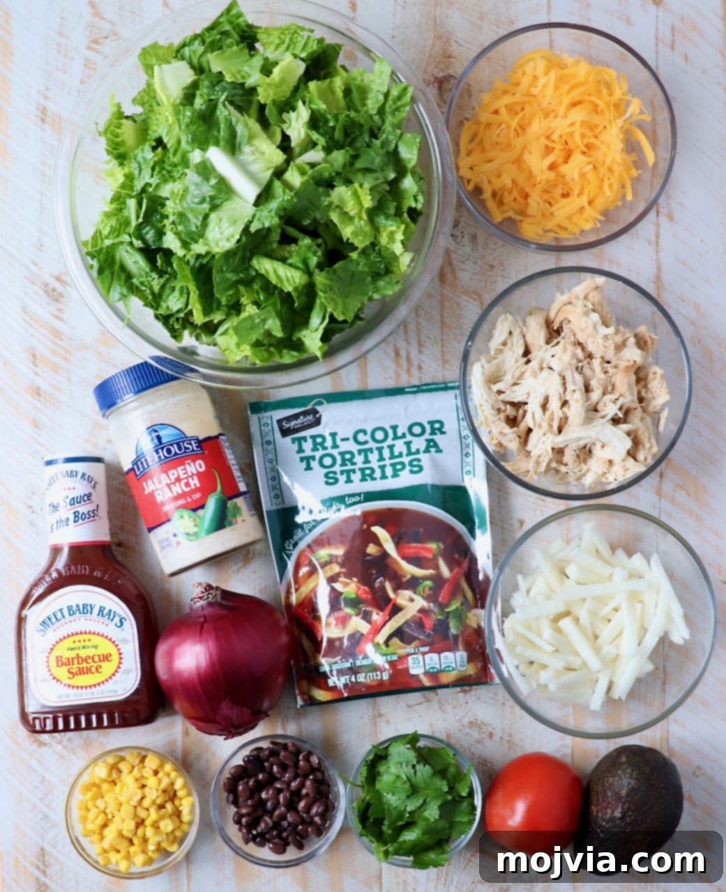 Ingredients for homemade BBQ Chicken Salad laid out on a white wooden board