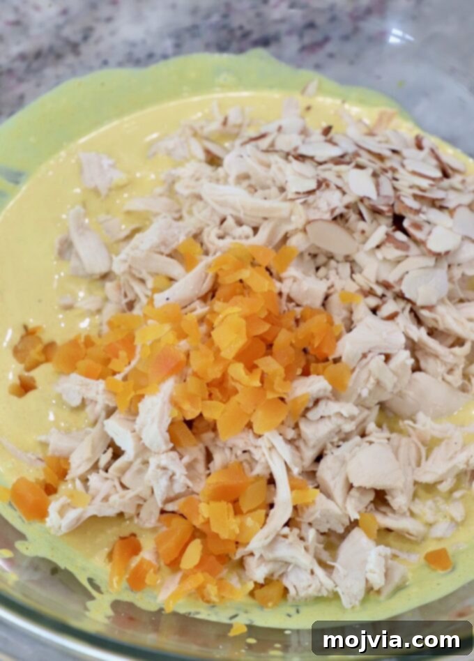 Crown Jewel Chicken Salad 9 cooked, shredded chicken in large glass bowl with creamy curry sauce and diced dried apricots
