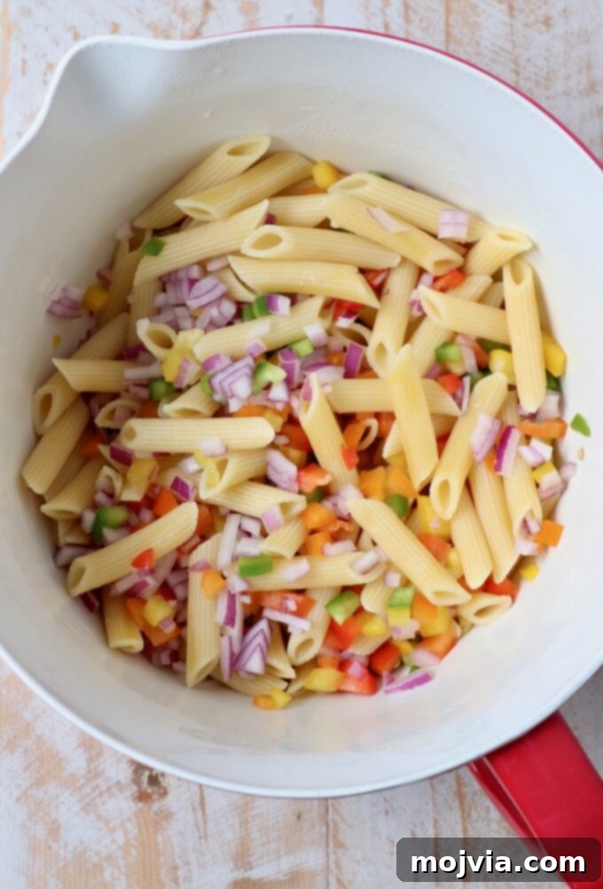 Refreshing Greek Yogurt Pasta Salad 5 Cooked penne pasta, diced bell peppers, and red onion in a large mixing bowl