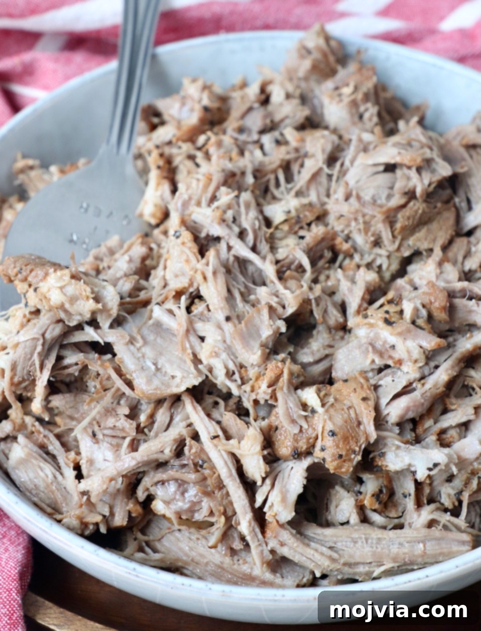 Quick and Tender Pressure Cooker Pork 11 pulled pork in a bowl with large serving fork