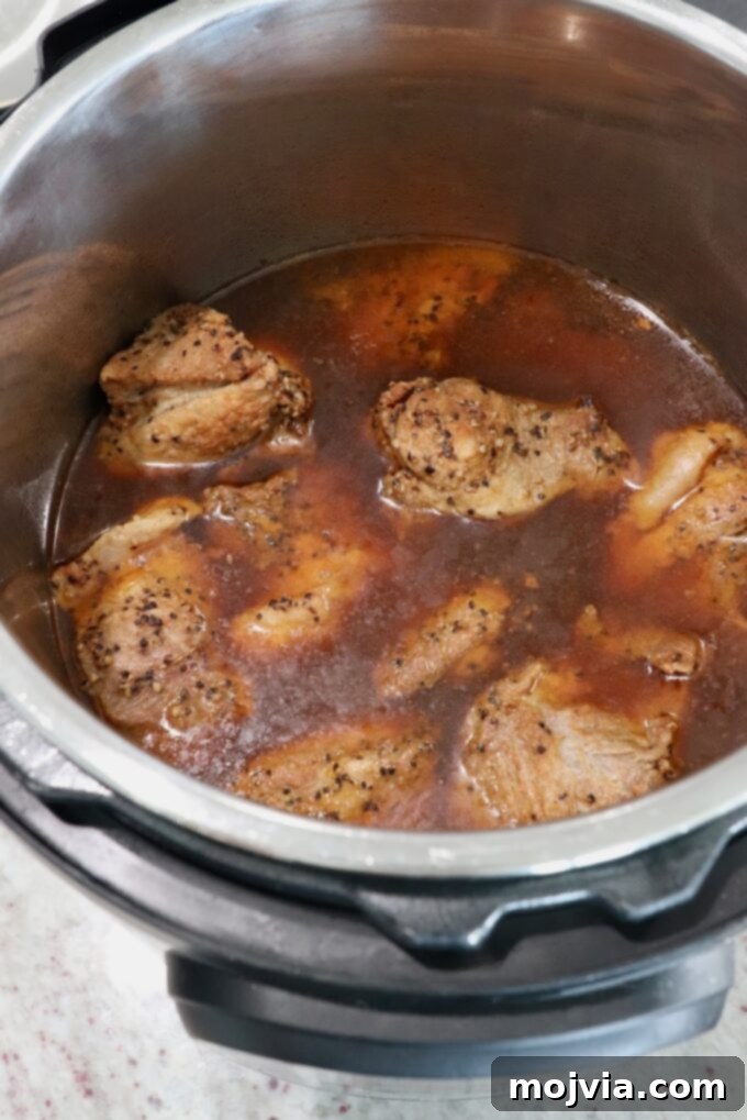 Quick and Tender Pressure Cooker Pork 8 cooked pieces of pork shoulder in Instant Pot with liquid