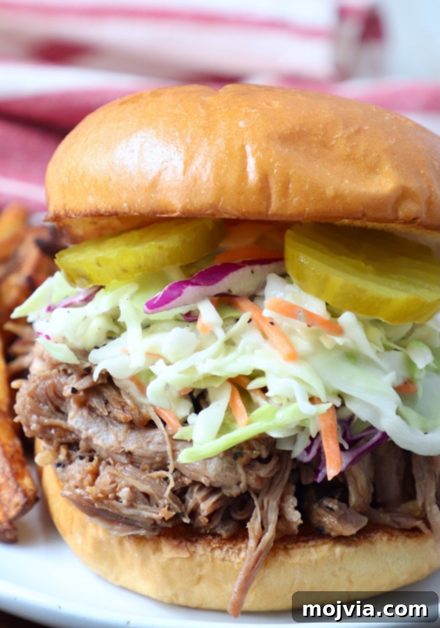 Quick and Tender Pressure Cooker Pork 10 pulled pork sandwich topped with coleslaw and pickles on plate