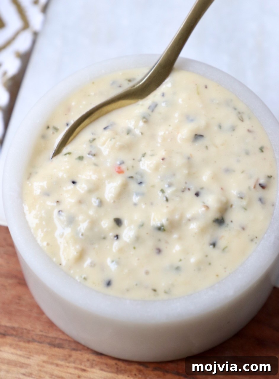 Creamy Garlic Parmesan Indulgence 2 Homemade creamy garlic parmesan sauce in a small bowl with a gold spoon, ready to be served