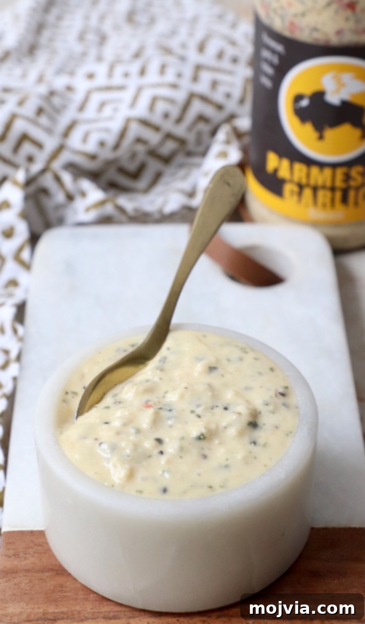 Creamy Garlic Parmesan Indulgence 4 Creamy garlic parmesan sauce in a small ceramic bowl with a spoon, showing its smooth texture