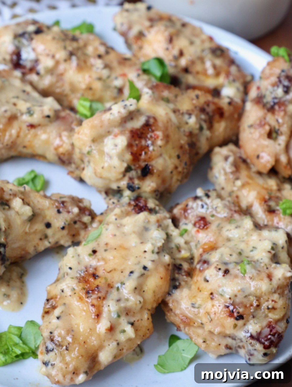Creamy Garlic Parmesan Indulgence 5 Garlic parmesan grilled chicken wings tossed with sauce on a white plate