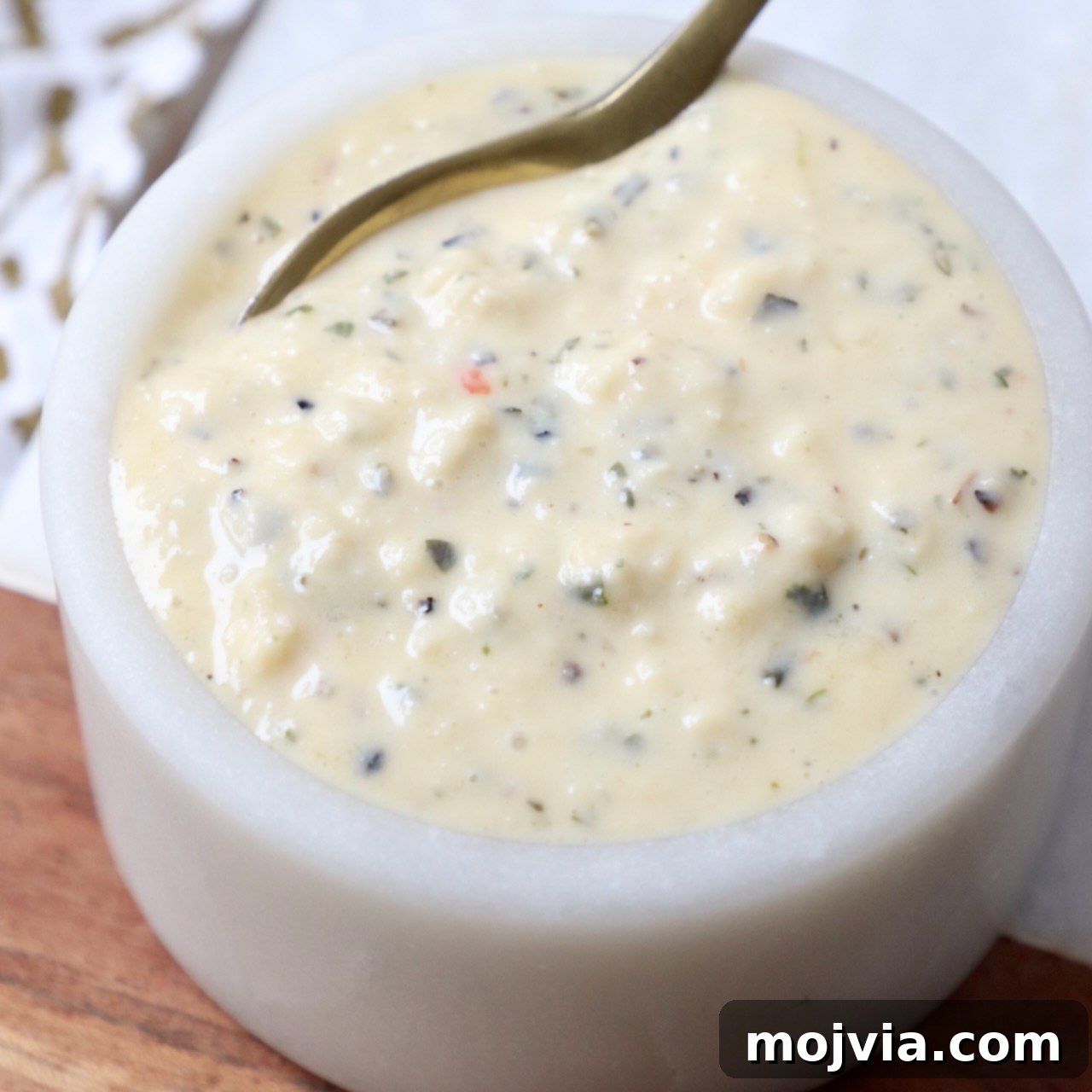 Creamy Garlic Parmesan Indulgence 6 Garlic parmesan sauce in a small bowl with a spoon, highlighting its texture and readiness