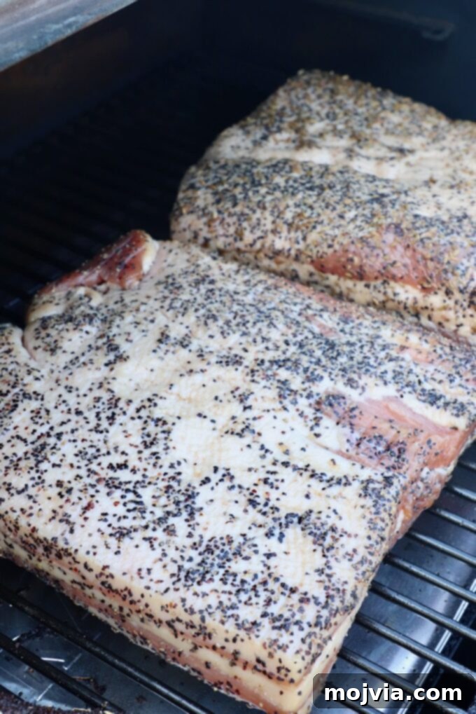 two seasoned pork bellies on a smoker