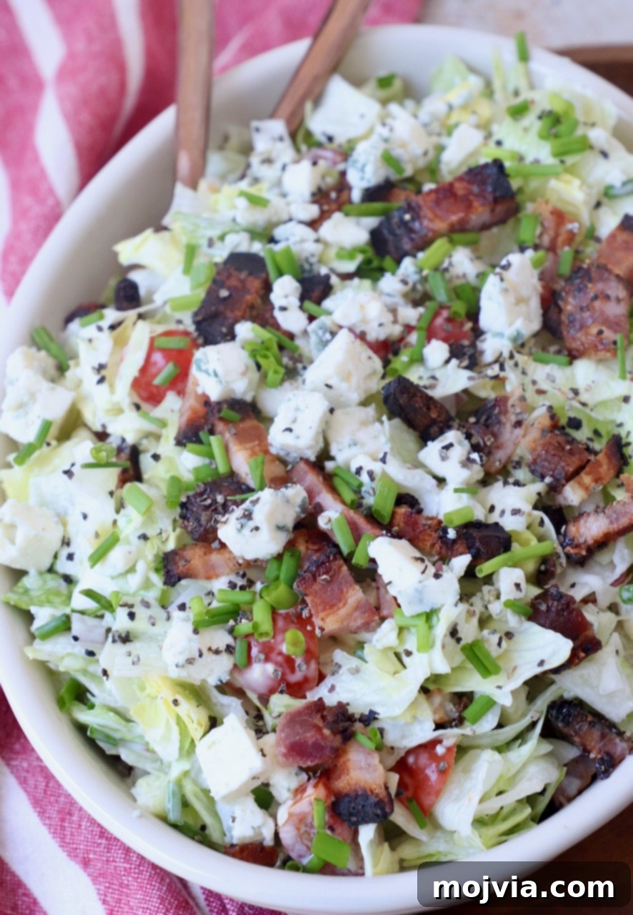Tangy Blue Cheese Greens 2 A vibrant bowl of chopped blue cheese salad, generously topped with crispy bacon pieces and fresh chives, ready to be served with a spoon.
