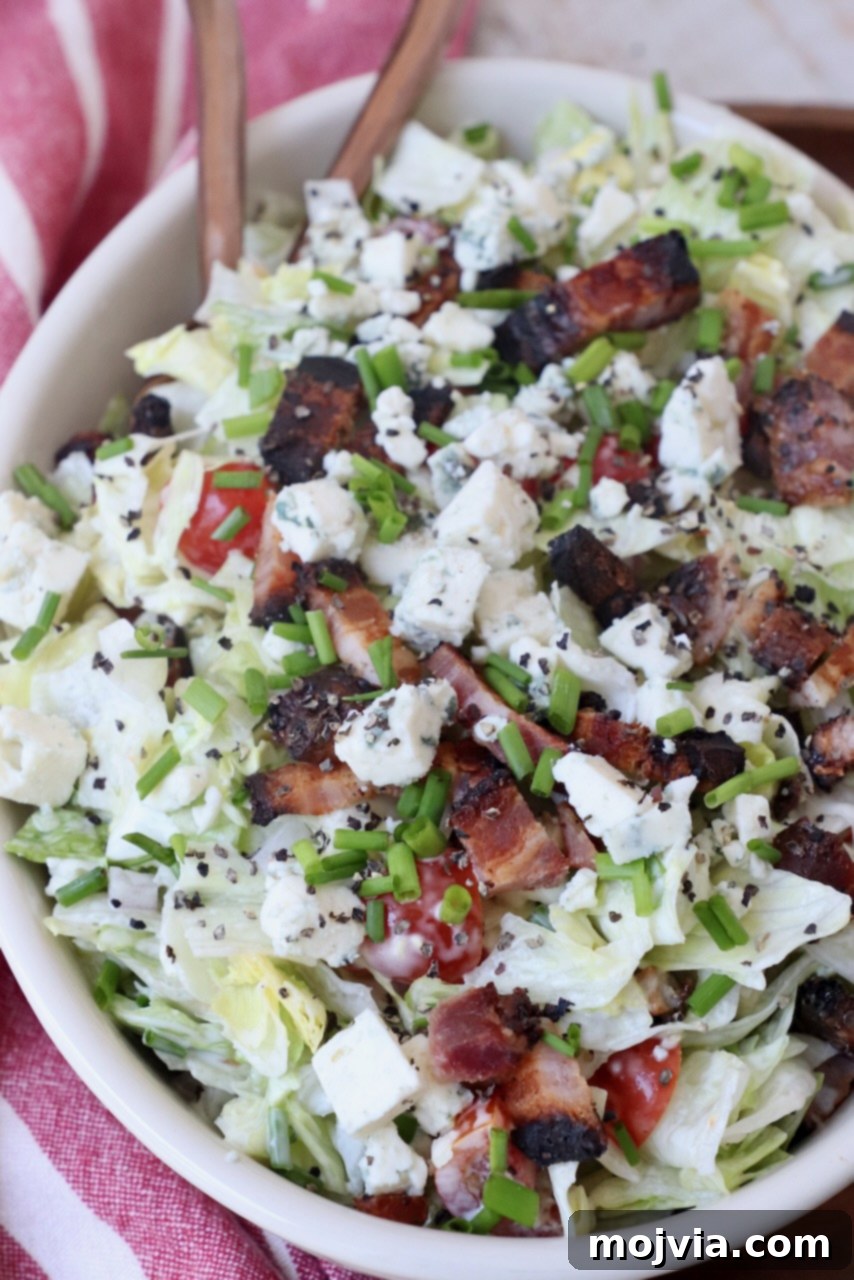 Tangy Blue Cheese Greens 5 An oval bowl filled with chopped blue cheese and bacon salad, ready for serving.