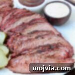sliced smoked tri tip on plate with bowls of bbq sauce
