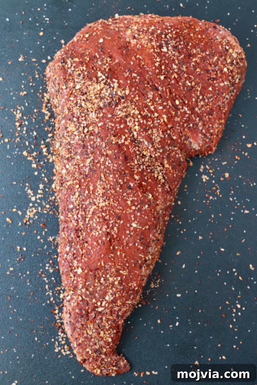 seasoned uncooked tri tip roast on cutting board