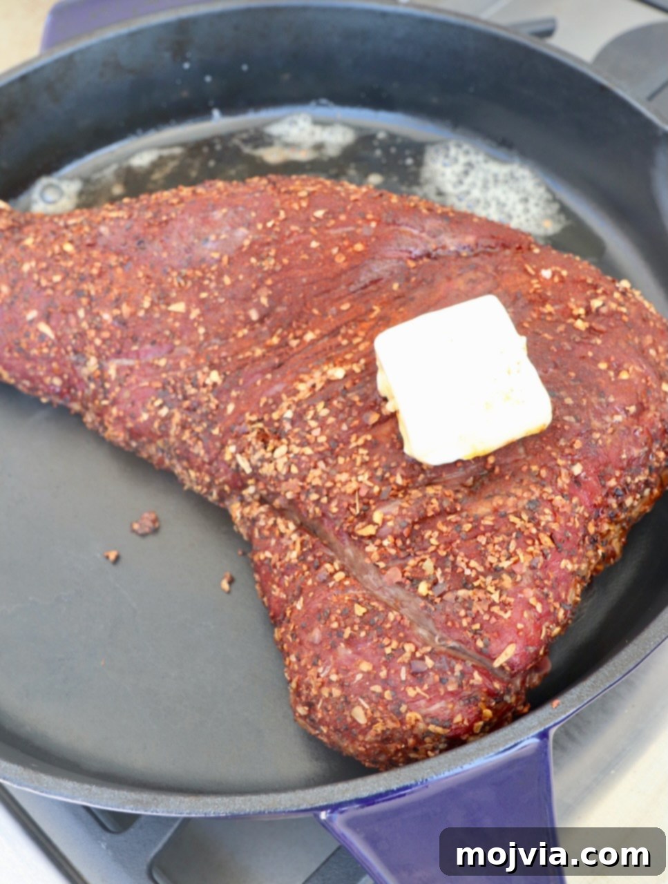 smoked seasoned tri tip in cast iron skillet topped with butter