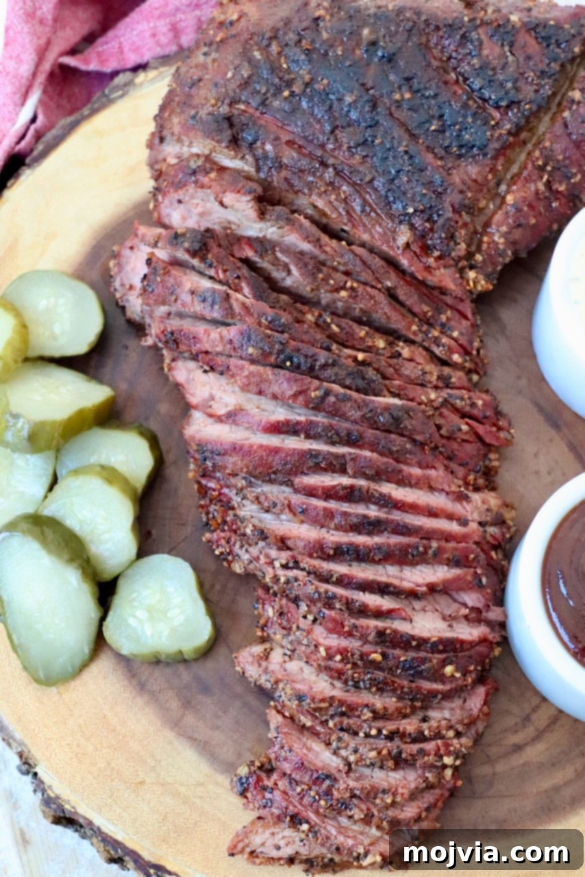 sliced smoked tri tip on cutting board with pickles