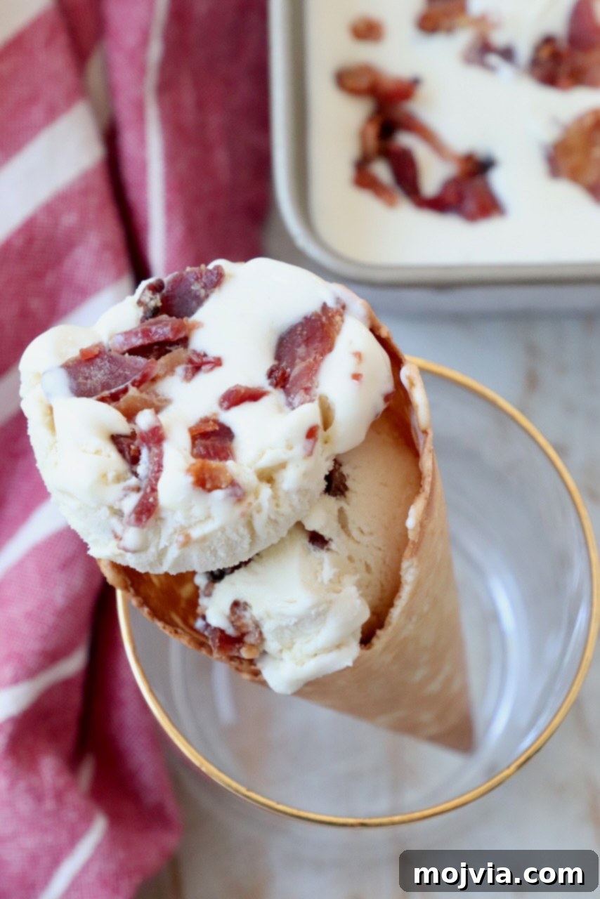 Maple Bacon No-Churn Ice Cream 11 Several scoops of maple bacon ice cream presented in a waffle cone, held upright in a drink glass.