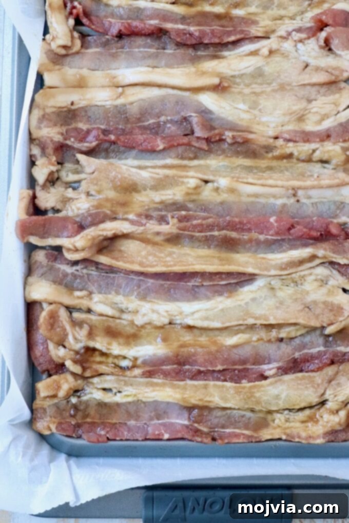 Maple Bacon No-Churn Ice Cream 4 Uncooked strips of thick-cut bacon coated in maple syrup and brown sugar, arranged on a wire rack over a foil-lined baking sheet.