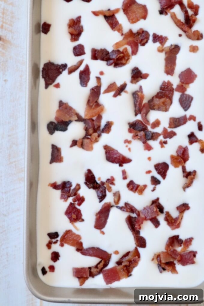 Maple Bacon No-Churn Ice Cream 9 Maple Bacon Ice Cream in a metal container, topped with reserved chopped candied bacon, ready to be frozen.