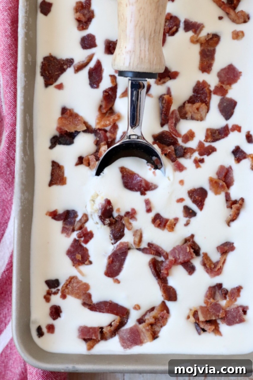 Maple Bacon No-Churn Ice Cream 10 Maple Bacon Ice Cream scooped into a metal container with an ice cream scoop, showcasing its creamy texture.