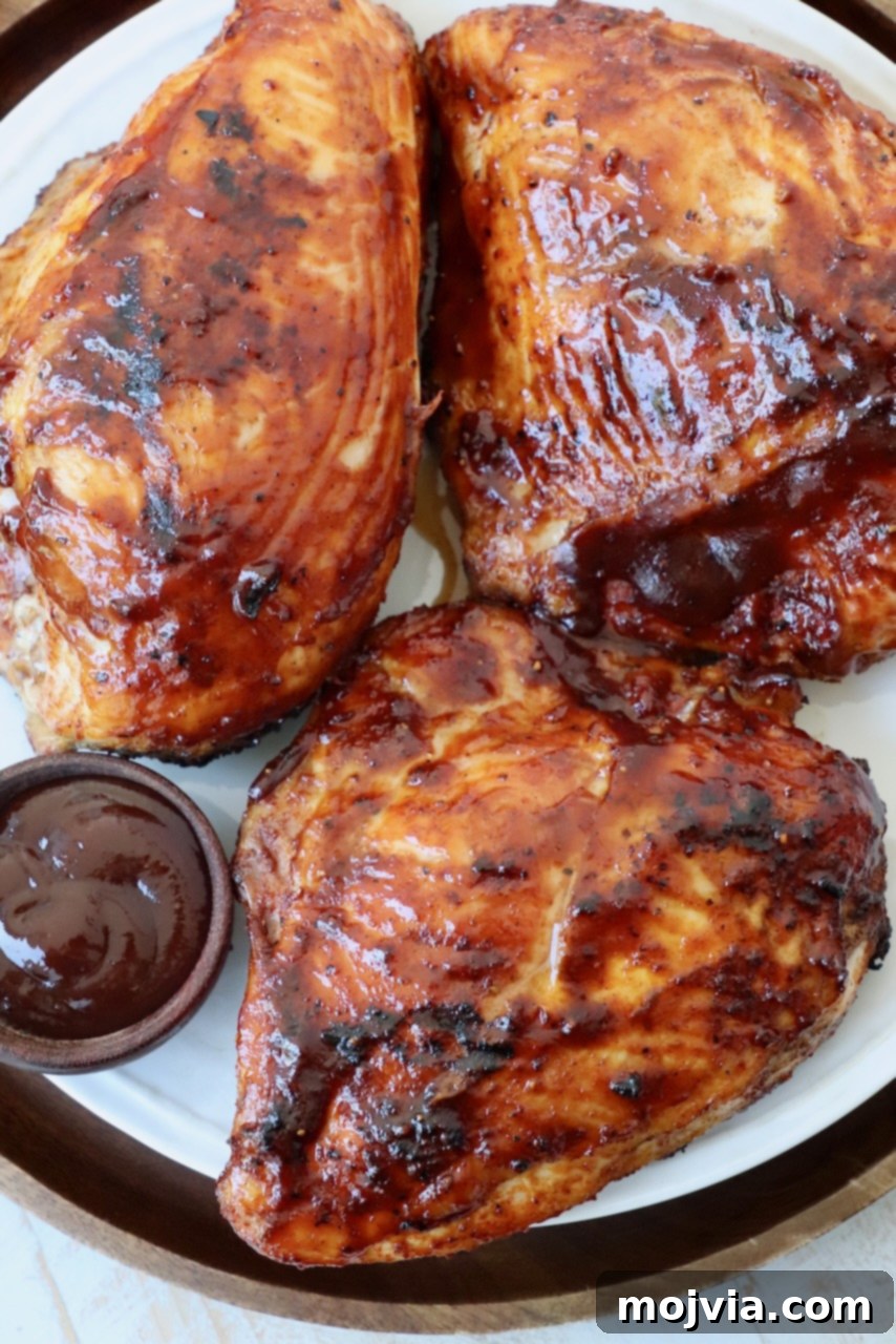 Smoked Chicken Feast 11 A plate of perfectly grilled chicken breasts, generously glazed with barbecue sauce, garnished with fresh herbs.