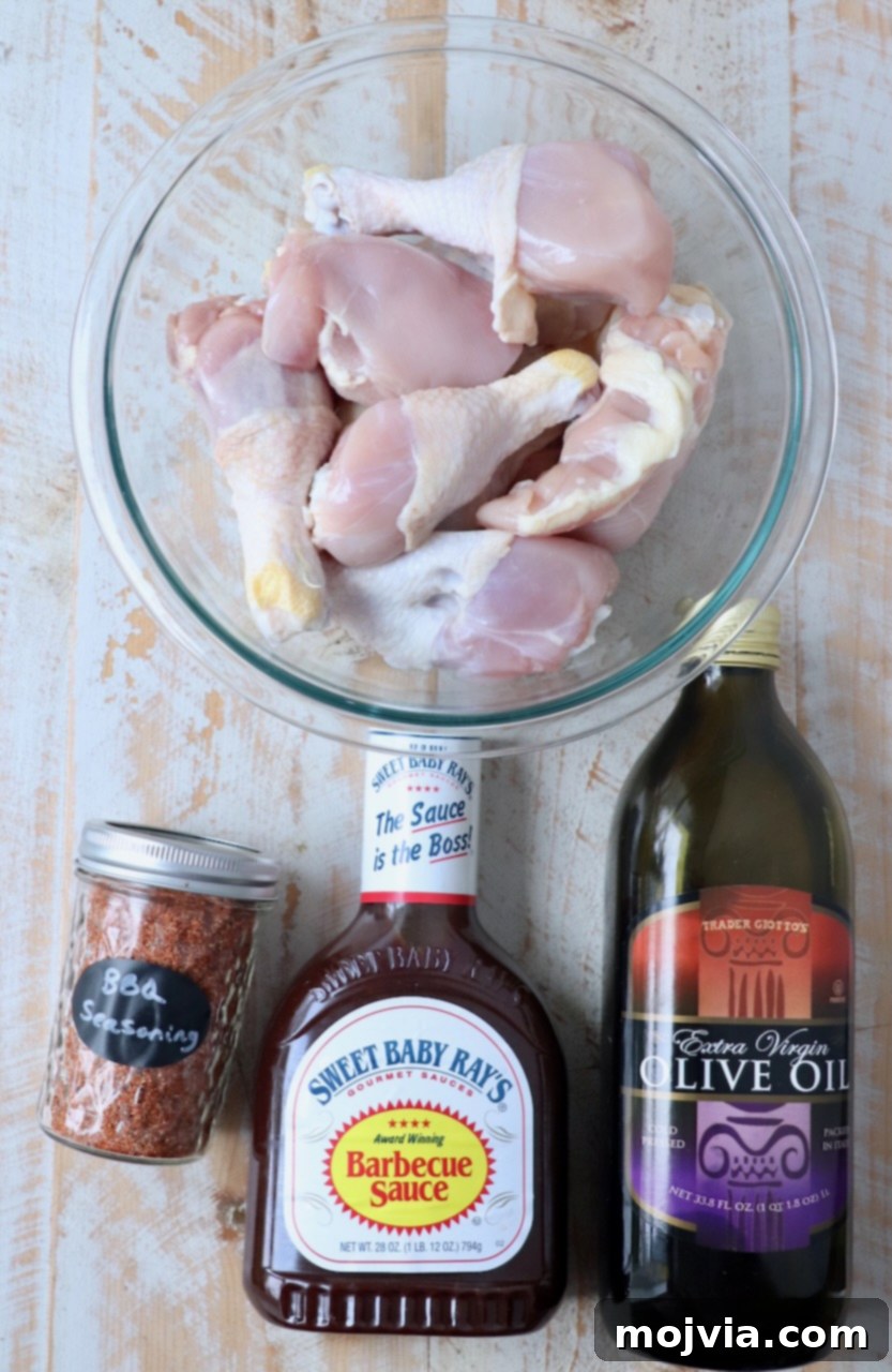 Smoked Chicken Feast 3 Various BBQ chicken ingredients laid out on a white surface: raw chicken pieces, olive oil, BBQ seasoning, and a bottle of barbecue sauce.