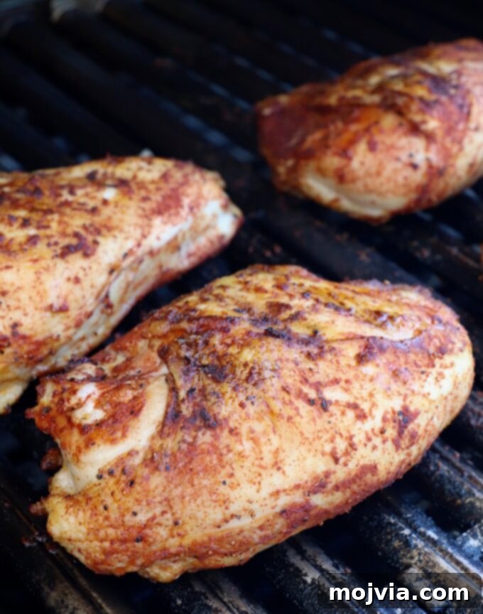 Smoked Chicken Feast 8 Partially cooked BBQ chicken pieces on the grill, some already flipped, showing developing color.