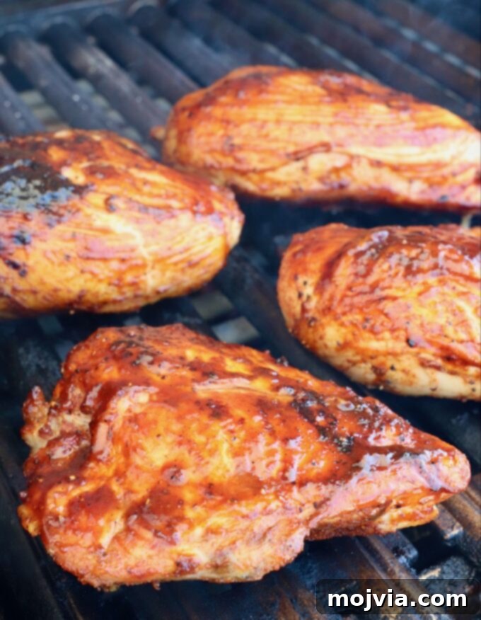 Smoked Chicken Feast 9 Close-up of chicken breasts on the hot side of the grill, being basted with barbecue sauce, creating a sticky glaze.