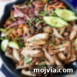 Grilled sliced chicken and sliced bell peppers and onions in a large skillet
