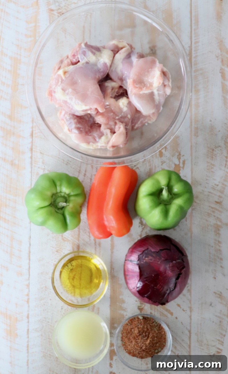 Fresh ingredients for chicken fajitas laid out on a white wooden board, including chicken, bell peppers, onions, limes, and spices