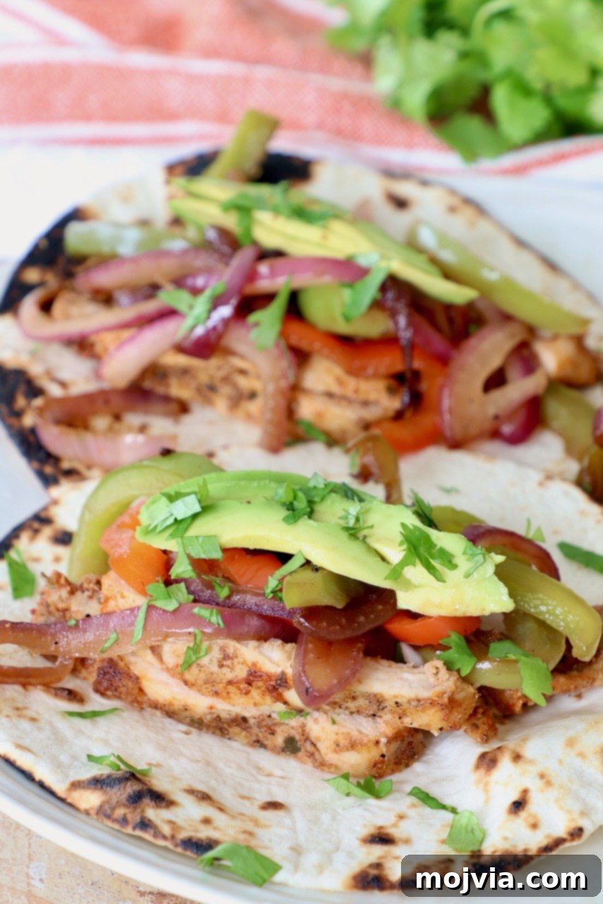 A vibrant plate of chicken fajitas topped with fresh cilantro and creamy sliced avocado, ready to be enjoyed