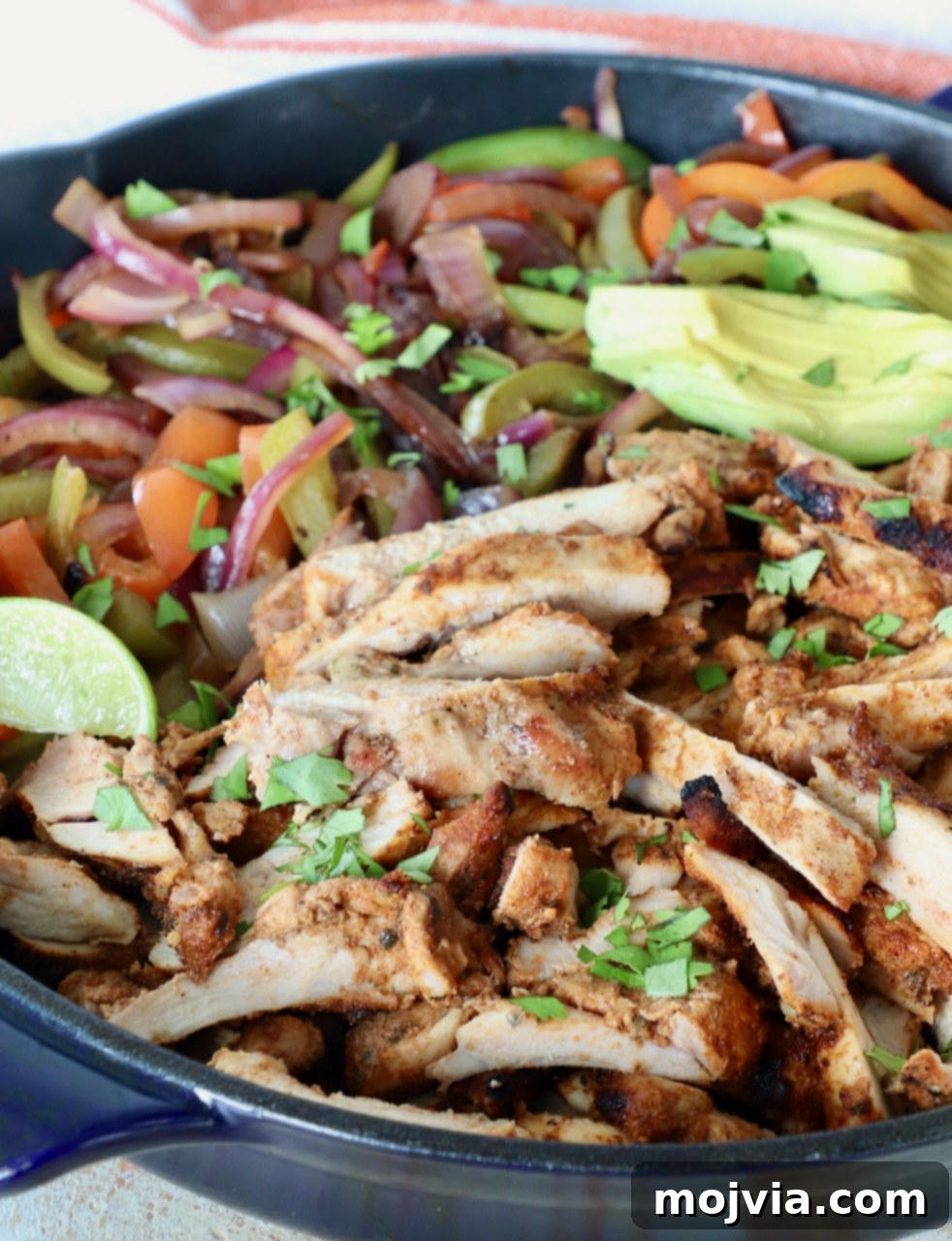 Slices of perfectly grilled chicken, bell peppers, and onions tossed together in a large cast iron skillet, ready to be served