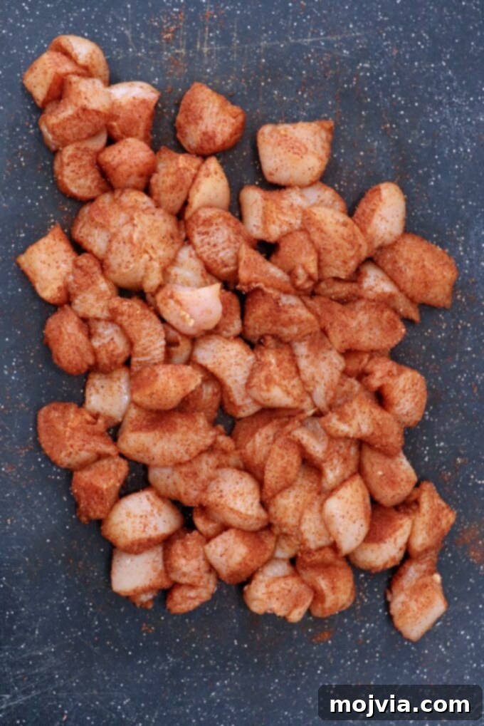 Crispy Boneless Bites 5 cubes of chicken breasts tossed with seasoning on cutting board