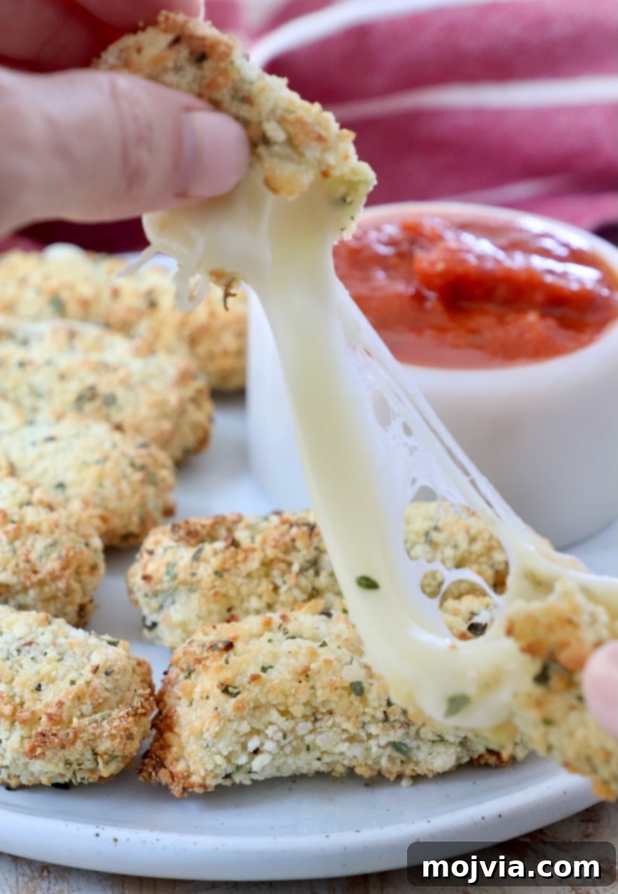 Crispy Air-Fried Mozzarella Sticks 11 A cooked air-fried mozzarella stick being pulled apart by hands, showcasing the long, stretchy, melted cheese inside, ready to be enjoyed.