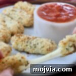 Crispy Air-Fried Mozzarella Sticks 12 hands pulling apart a mozzarella stick, revealing melted cheese