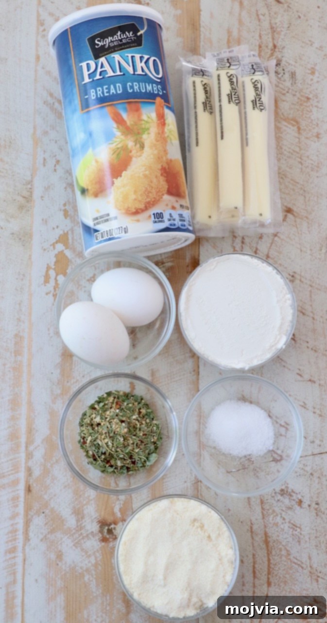 Crispy Air-Fried Mozzarella Sticks 3 Fresh ingredients for making air fryer mozzarella sticks laid out on a white wooden board, including string cheese, eggs, flour, breadcrumbs, and seasonings.