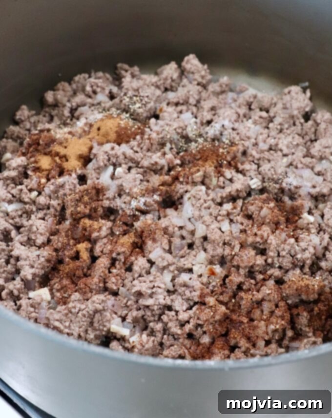 Creamy Greek Comfort Bake 6 Seasoned, cooked ground beef, beautifully browned, sits in a large skillet after being drained of excess grease.