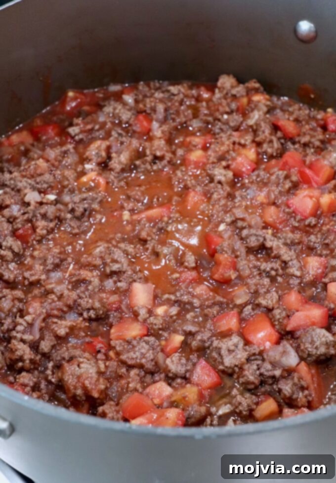 Creamy Greek Comfort Bake 8 A rich, deeply flavored ground beef and tomato sauce, infused with Greek spices, simmering gently in a large skillet.