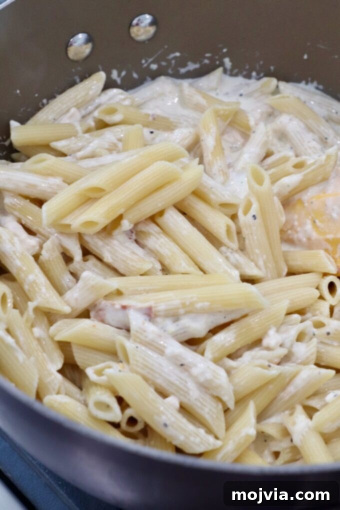 cooked pasta tossed with white sauce in a large pan