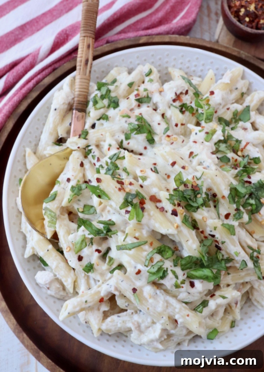 cooked garlic parmesan chicken pasta in bowl topped with chopped green onions
