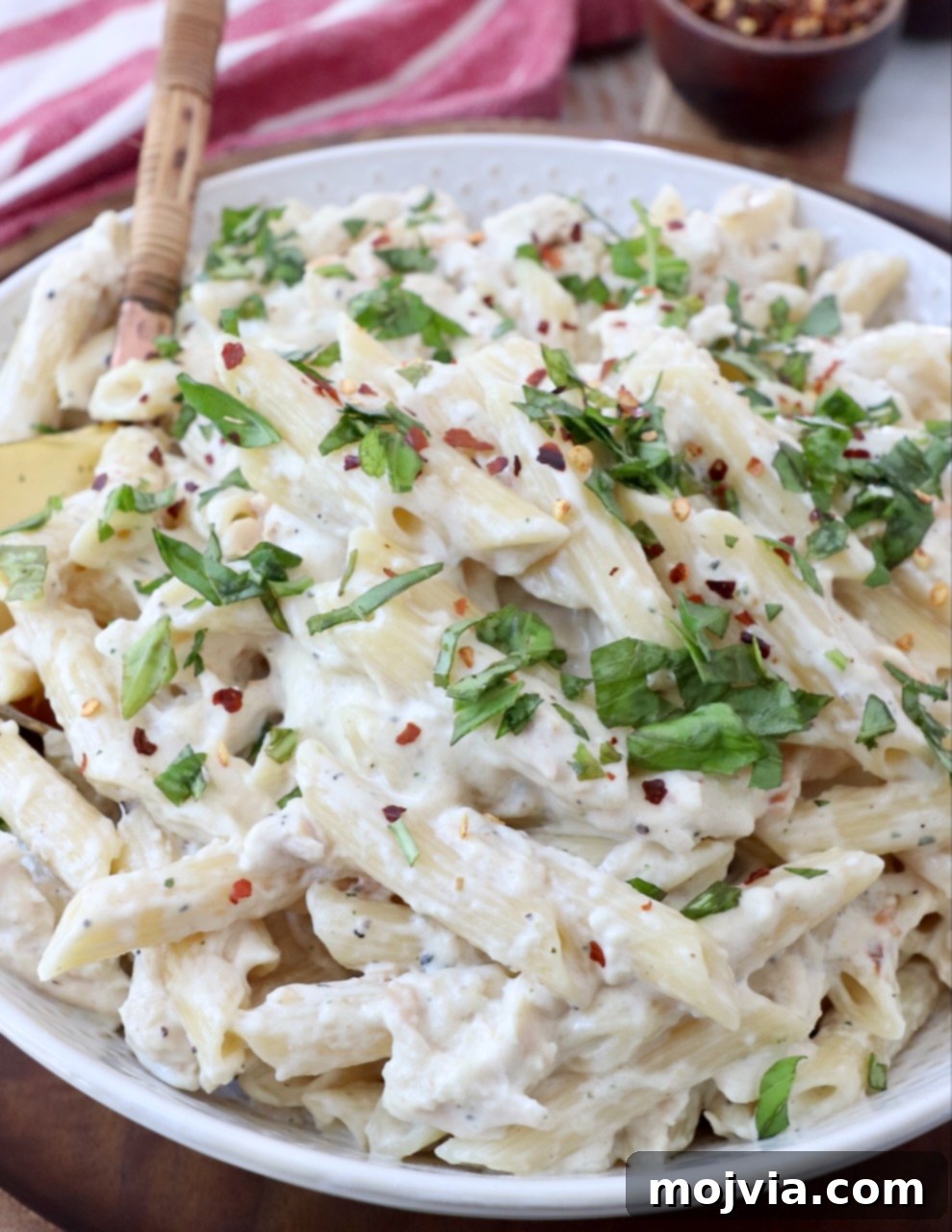 creamy chicken pasta in bowl with serving spoon, ready to be served