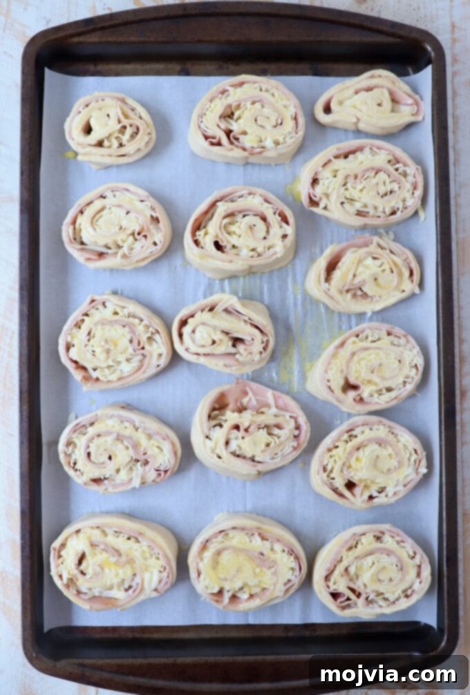 uncooked monte cristo rolls on parchment-lined baking sheet
