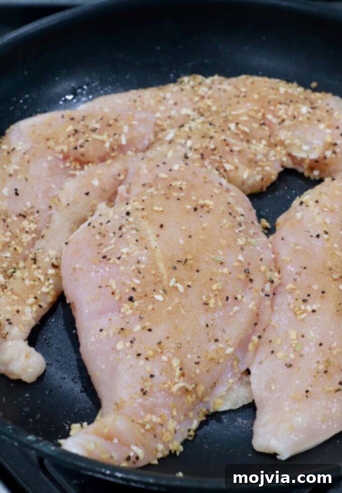 Rich Slow Cooker French Onion Chicken 7 Raw, seasoned chicken breasts searing in a skillet.