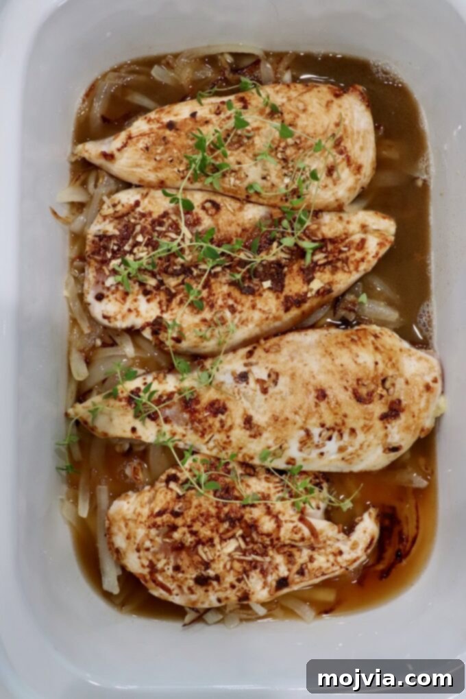 Rich Slow Cooker French Onion Chicken 9 Seared chicken breasts in a slow cooker with fresh thyme sprigs and caramelized onions.